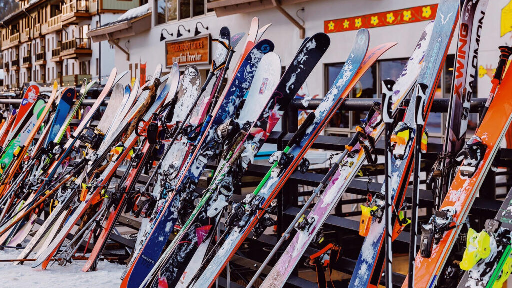 Skis and snowboards lined up outside in fresh snow