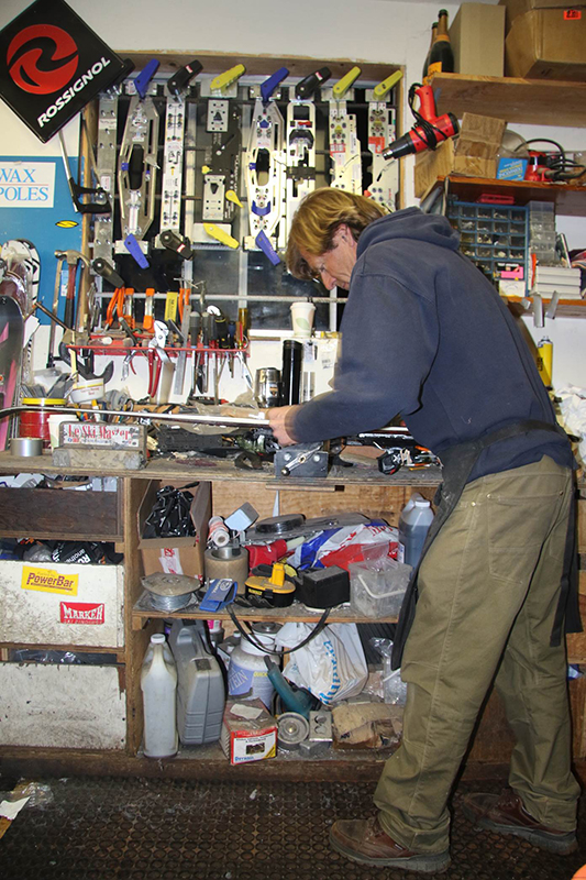 A man at a work table tuning skis