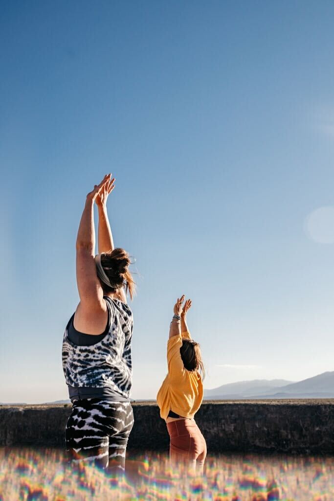 Two women practice yoga outdoors in the desert