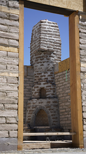 A kiva fireplace, made from adobe bricks, under construction.