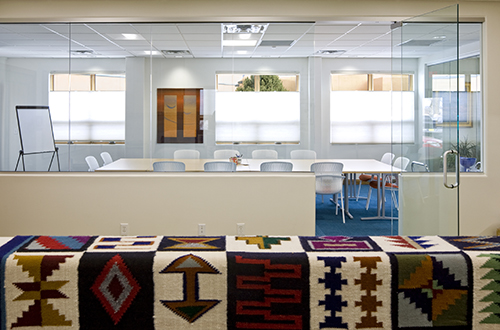 A modern, light and bright office with a traditional woven rug on display.