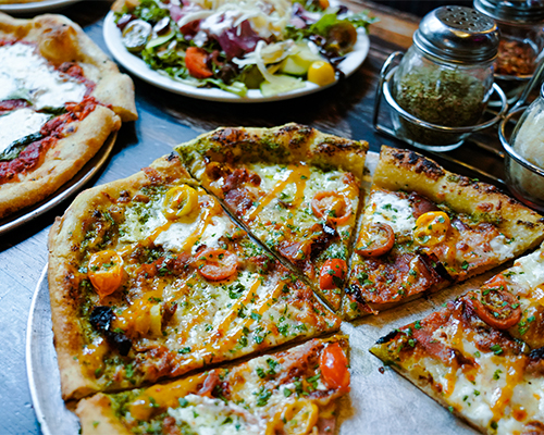 A wood fired pizza and salads on a table