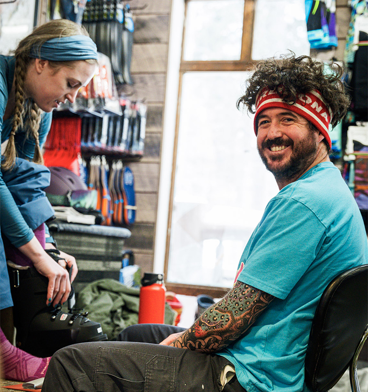 A ski boot fitter smiles as he helps a customer.