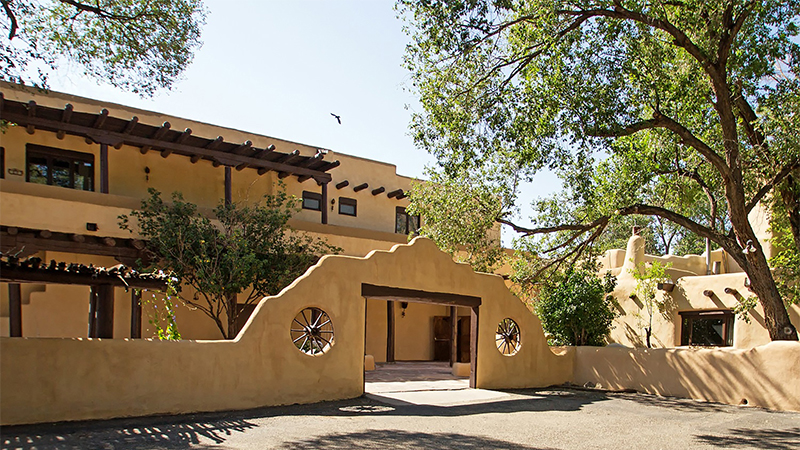 Southwestern adobe walls surround a tree filled courtyard.