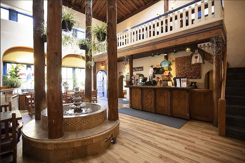 A fountain with large wooden columns surrounding it in the center of a hotel lobby with wood floors.