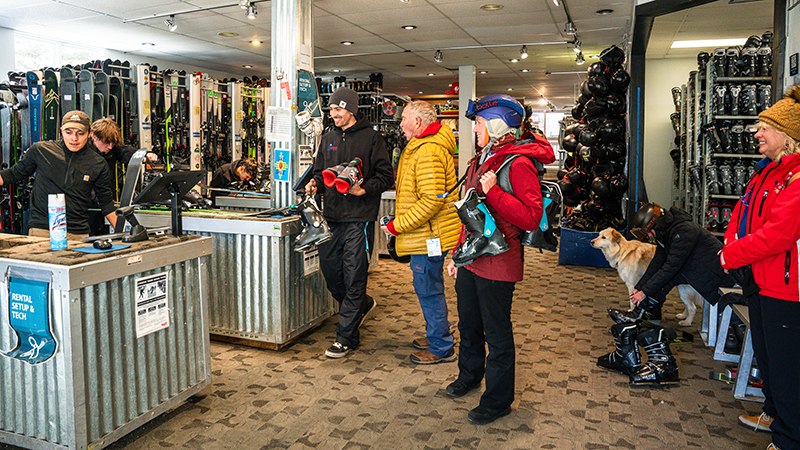 An older couple are assisted in a ski shop by a smiling employee.