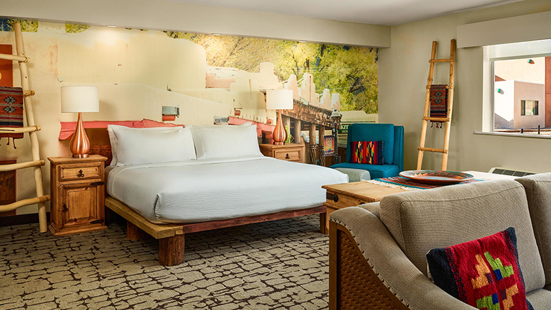 A southwestern decorated hotel room with a low king bed and white linens.