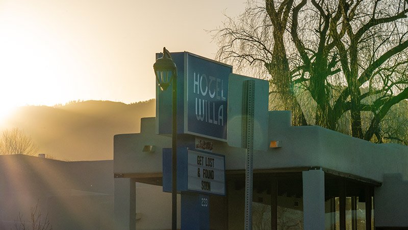 A sign for "Hotel Willa" in front of s bright sunrise.