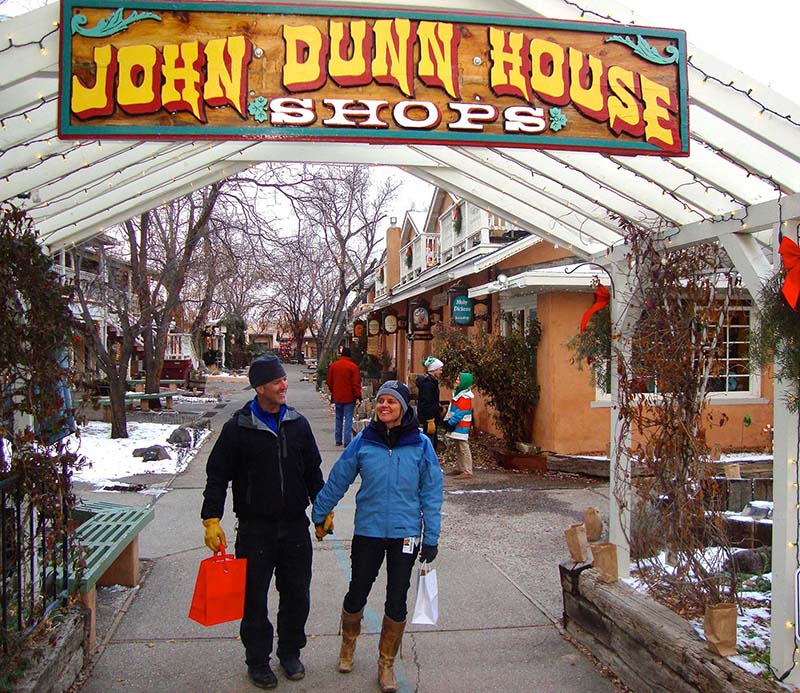 A couple walks hand in hand through a snowy outdoor mall.