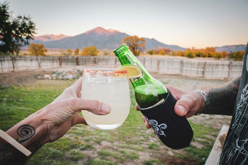 A margarita and a beer cheers in front of a mountain.