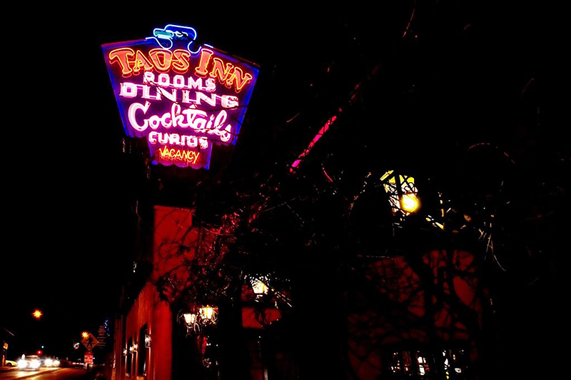 A neon sign lights up the night for an Inn with vacancy and cocktails.