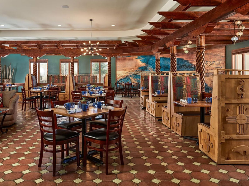 The southwestern style interior of a restaurant with wooden carved booths and several tables for seating.