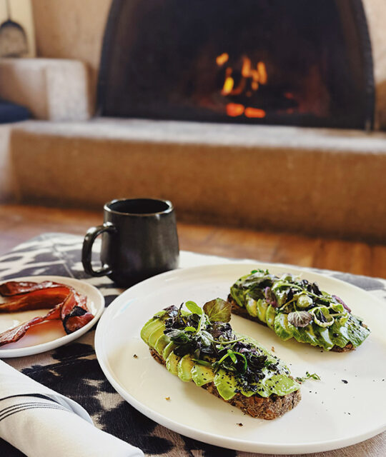 Avocado toast topped with microgreens, bacon and coffee.