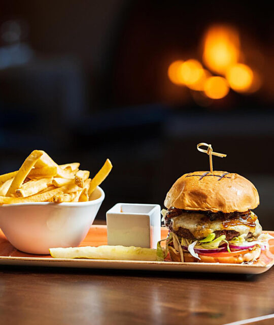 Gourmet burger and fries in front of a fireplace