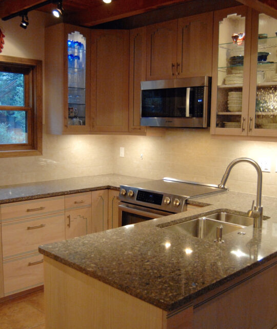 A bright, clean kitchen with granite counters and glass door cabinets