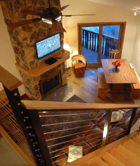 A modern staircase leading to a living space with a stone fireplace