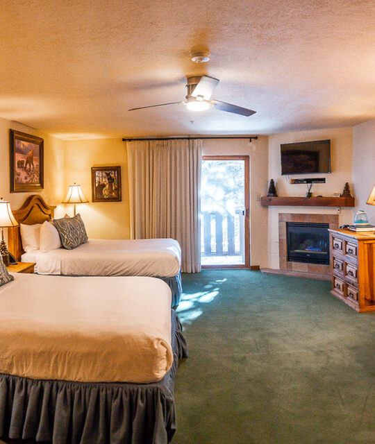 Two queen bed hotel with fireplace and deck.