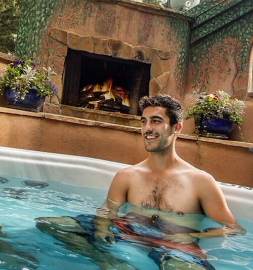 A couple smiles at each other in an outdoor hot tub