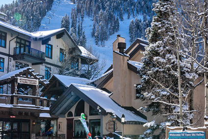 Skier walking past Alpine Village Suites in Taos Ski Valley.