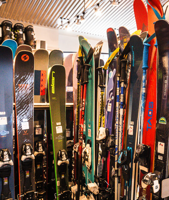 Line up of rental skis in a gear shop.