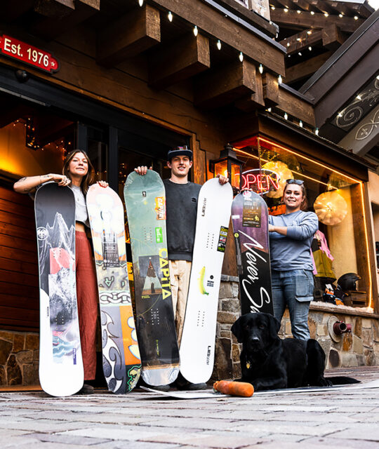 Friendly employees with snowboards at Big K's Surf Shop Thunderbird in Taos Ski Valley