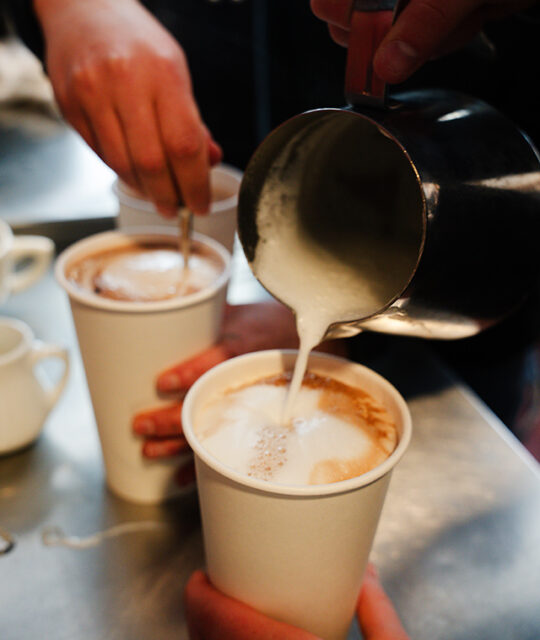 Pouring frothed milk into a coffee to go.