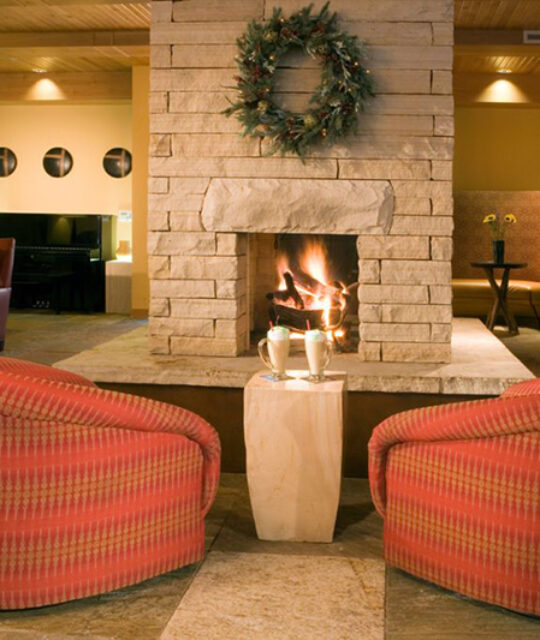 Two lounger chairs by a fireplace with drinks