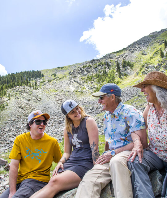 A group of hikers take a break in front of a scree field