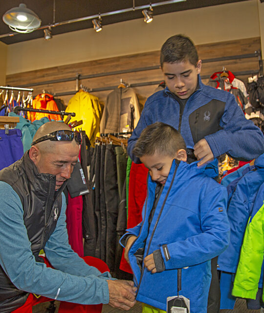 Cottam's Ski Shop staff helping boy with ski jacket