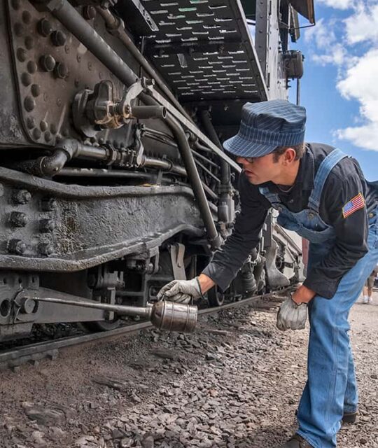 Man oiling an historic railroad stream engine.