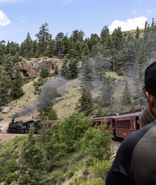 Passenger in an open car enjoying a historic steam train excursion.