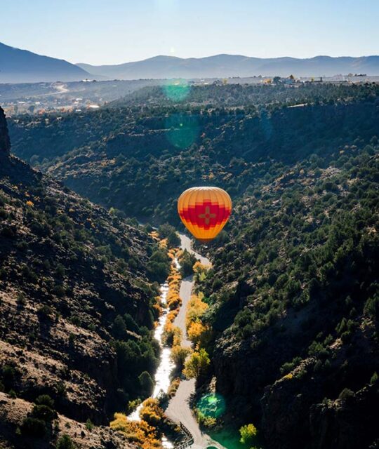 Hot air balloon flying in a river gorge.