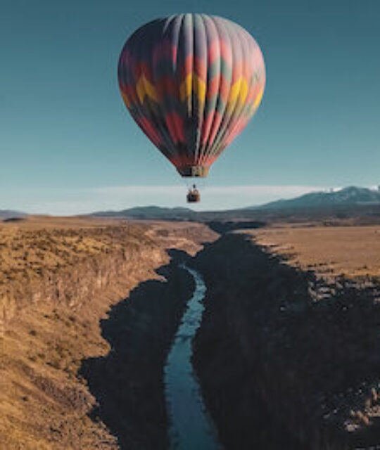 Hot air balloon floating over river.