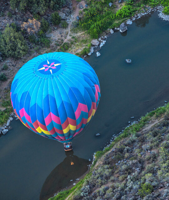 View over a colorful hot air balloon between the river banks.