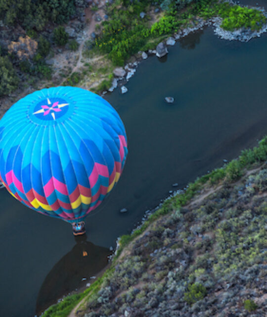 View over a colorful hot air balloon between the river banks.