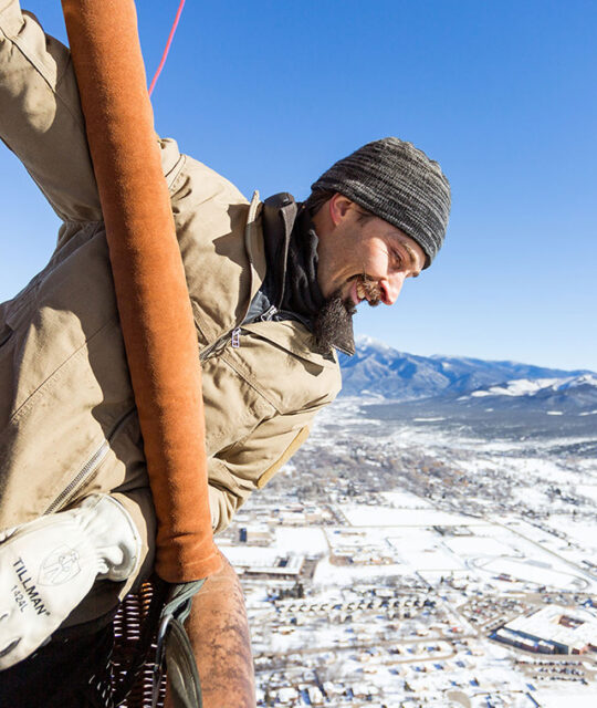 Rio Grande Balloons owner Sol Lothe looking out over basket onto snow covered mesa.