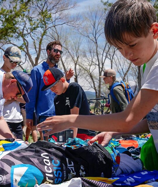 Kids at a bike swap looking through cycling apparel.