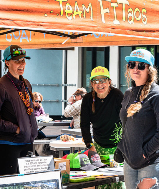 Women working an event under a Team FITaos canopy