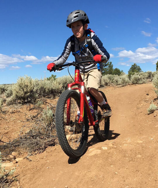 FITaos boy mountain biking in on dirt trail