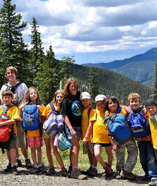 Group of kids hiking in the mountains wearing their backpacks funny.