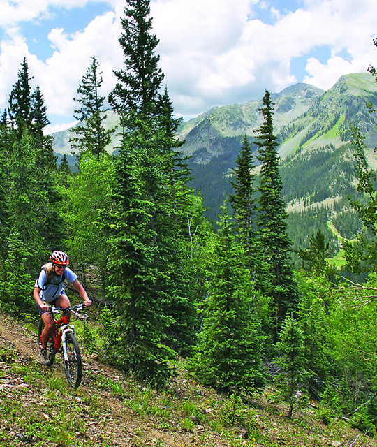 Woman mountain biking the Overlook Trail with Kachina Peak in the background