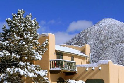 Large Taos adobe home in winter with snow