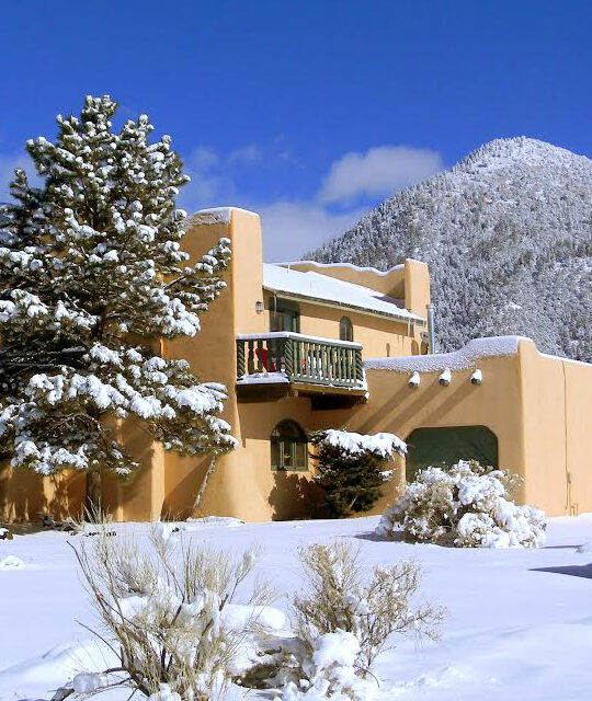 Large Taos adobe home in winter with snow