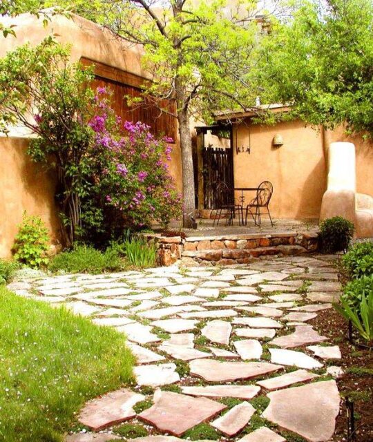 Courtyard of an adobe home with Lilac trees blossoming