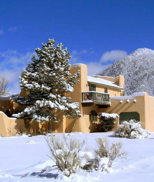 Large Premiere Properties Taos adobe home in winter with snow