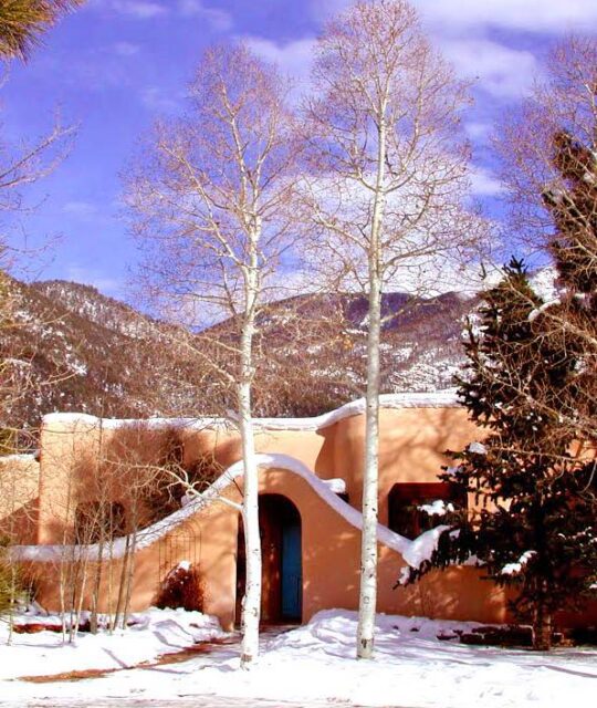 Beautiful adobe home entrance with aspen trees in the winter with snow