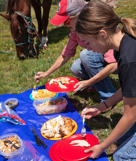 Horseback tours riders enjoying a picnic lunch and the horse is too.