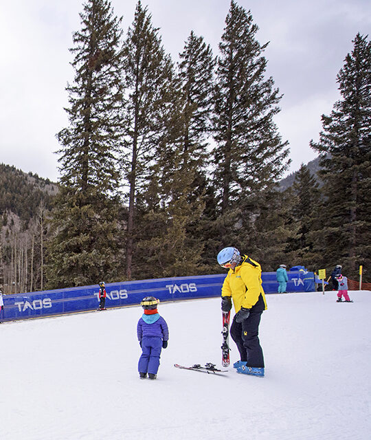 Children's ski instructor and child on ski slope in Taos