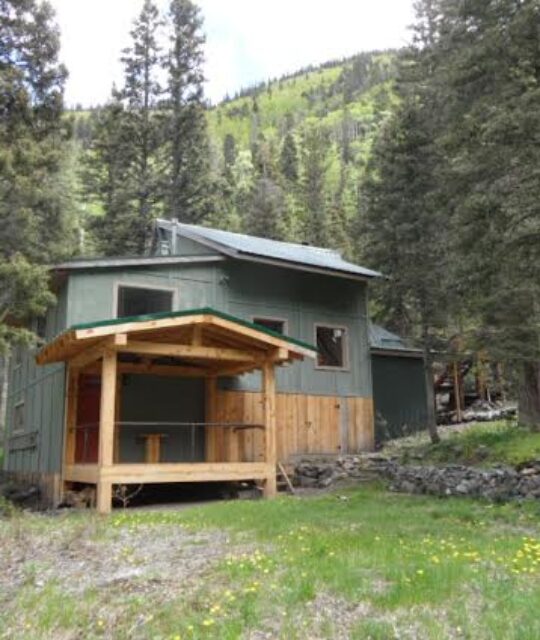 Engels & Volker - A painted wooden cabin nestled in the fir trees