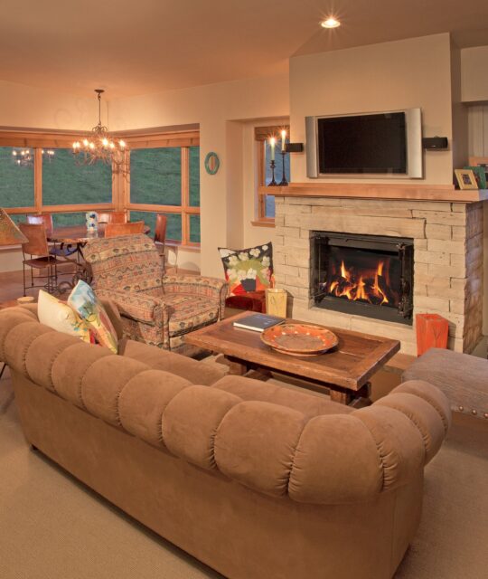 Engel & Volkers A plush beige couch in a living area with a stone fireplace